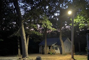 Ein Haus mit einer Veranda, umgeben von Bäumen, unter einer Straßenlaterne.
