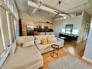 A modern living space with a sectional sofa, a dining area, and a kitchen.