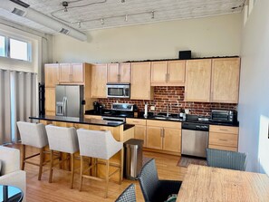 A modern kitchen with wooden cabinets, stainless steel appliances, and a central island with bar stools.