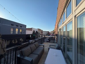 A rooftop patio with outdoor seating, a view of the street, and a building with a sign for 'Kern Arnold Real Estate'.