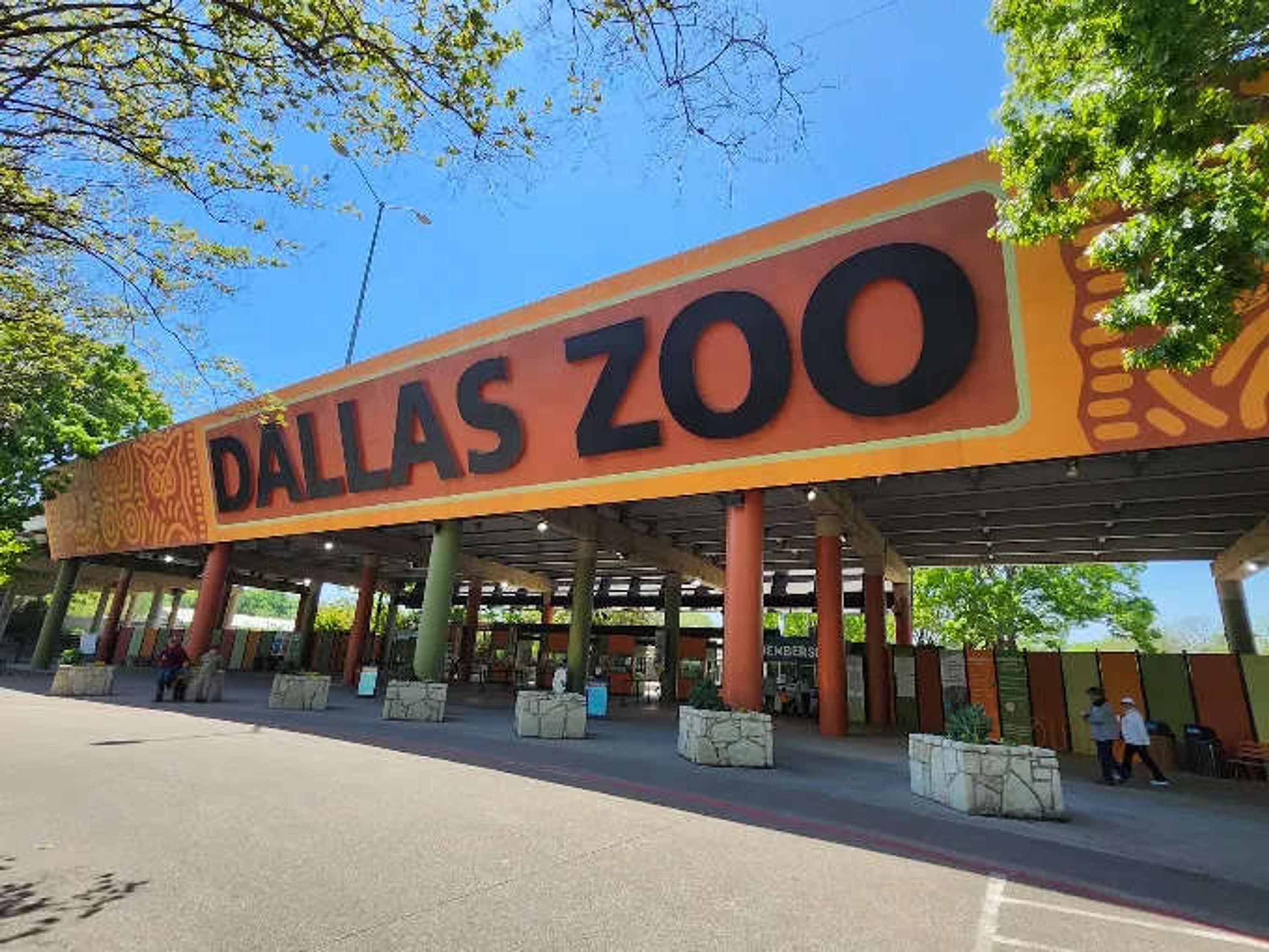 A large sign for the Dallas Zoo with a canopy structure overhead.