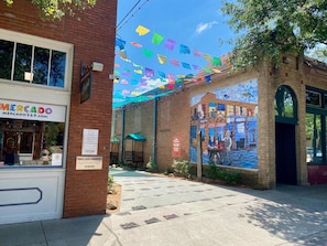 A street with a brick building, a mural, and colorful flags. - Bishop Arts 6BR 6BA Townhouse Sleeps 12 Parking (Dallas)