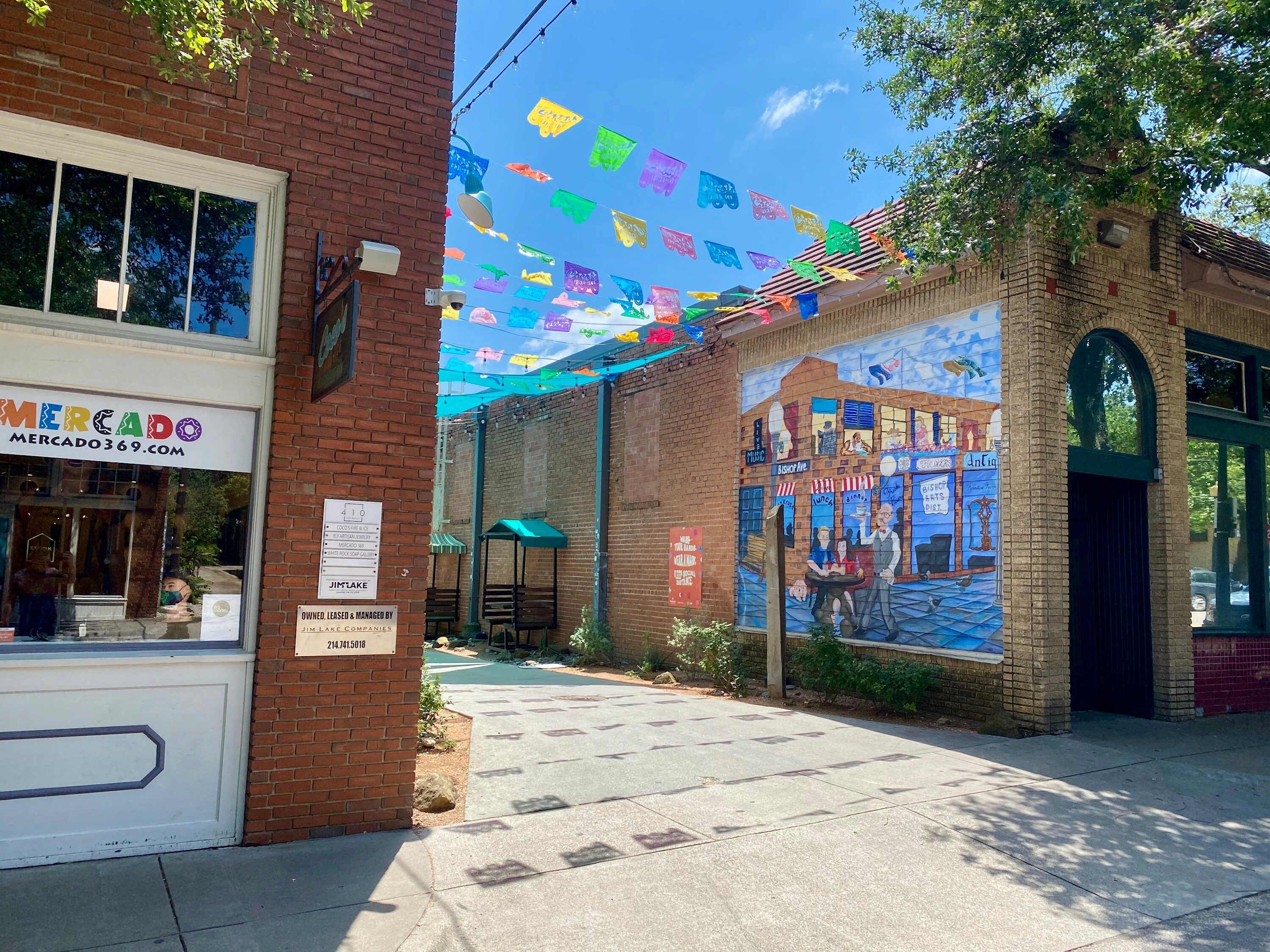 A street with a brick building, a mural, and colorful flags.