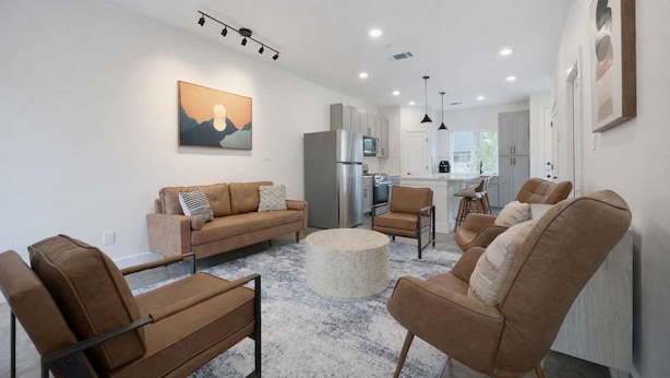 A modern living room with a sofa, chairs, and a coffee table. - Bishop Arts 6BR Townhouse Sleeps 12 Close to DT (Dallas)