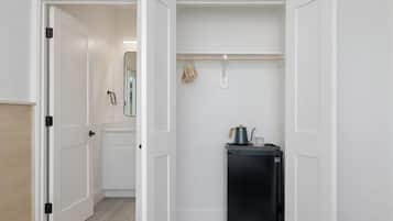 Una cocina compacta con un refrigerador negro, una tetera y un tendedero.