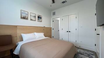 A hotel room with a bed, a ceiling fan, a TV, and a door with a coat closet.