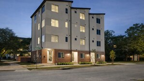 Un edificio de varios pisos con techo plano, ventanas rectangulares y fachada de ladrillo en la planta baja.