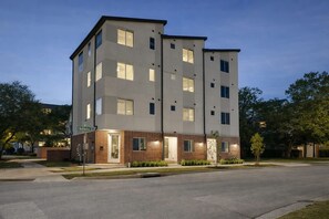 Um edifício de vários andares com telhado plano, janelas retangulares e fachada de tijolos no nível térreo.