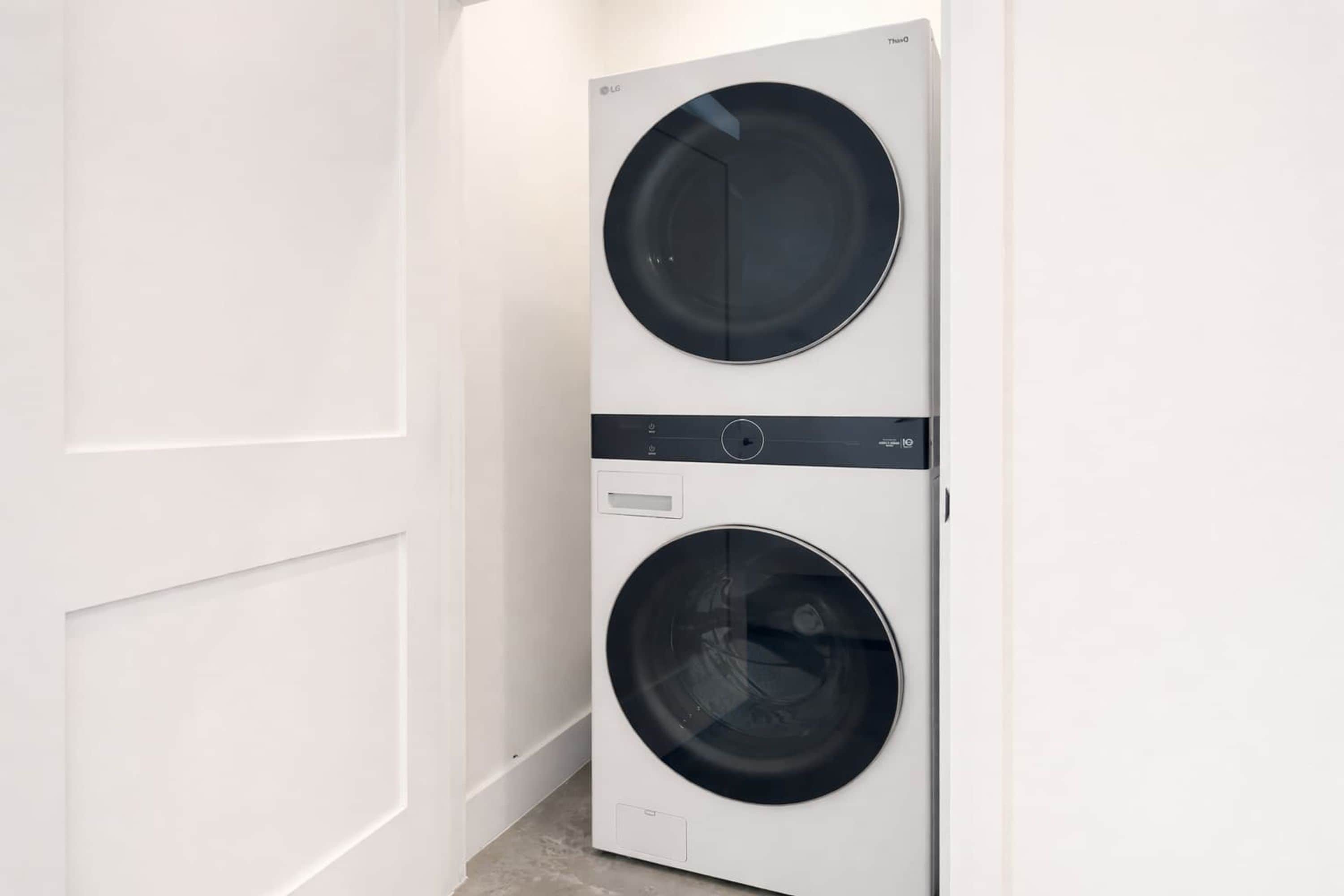 A white wall-mounted washer and dryer unit with a control panel and a small storage compartment.