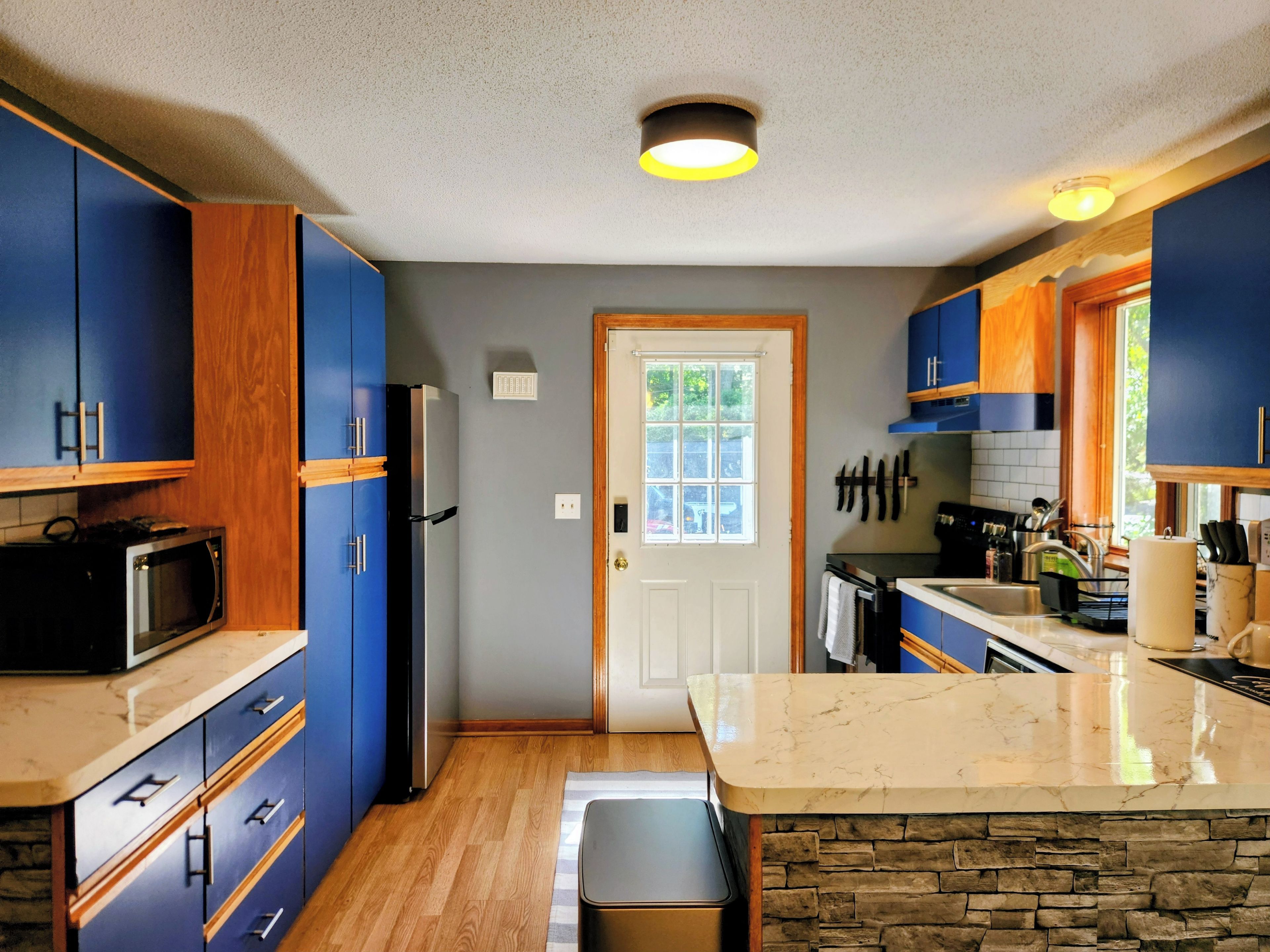Eine moderne Küche mit blauen Schränken, einer Marmorarbeitsplatte und einer Steinrückwand.