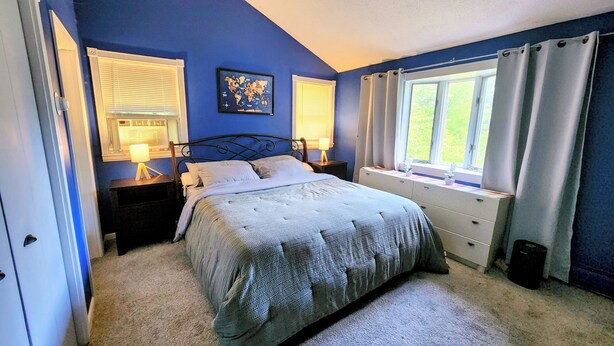 Un dormitorio con cama, mesitas de noche, una ventana con cortinas y un mapa del mundo en la pared.