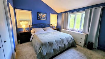 A bedroom with a bed, bedside tables, a window with curtains, and a world map on the wall.