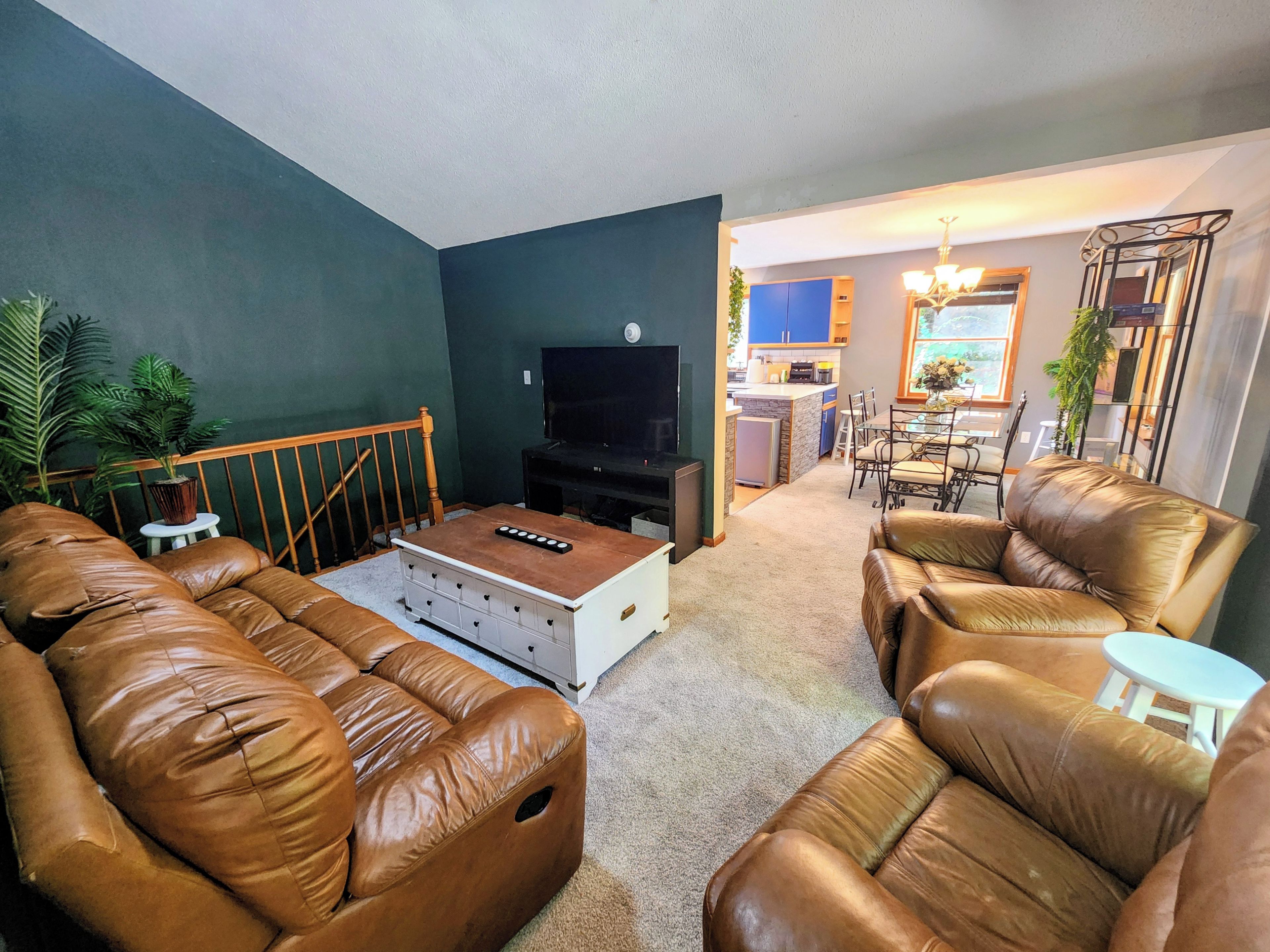 A living room with a TV, leather sofas, a coffee table, and a small side table.