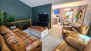 Una sala de estar con televisor, sofás de cuero, una mesa de centro y una mesita auxiliar.