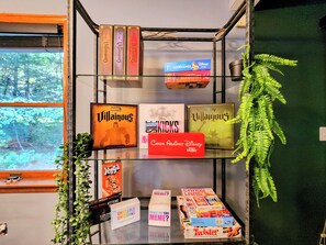 A shelf with various board games and a fern plant.