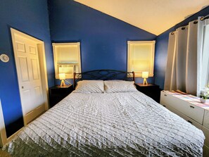 A bedroom with a bed, two bedside tables with lamps, a dresser, and a door.