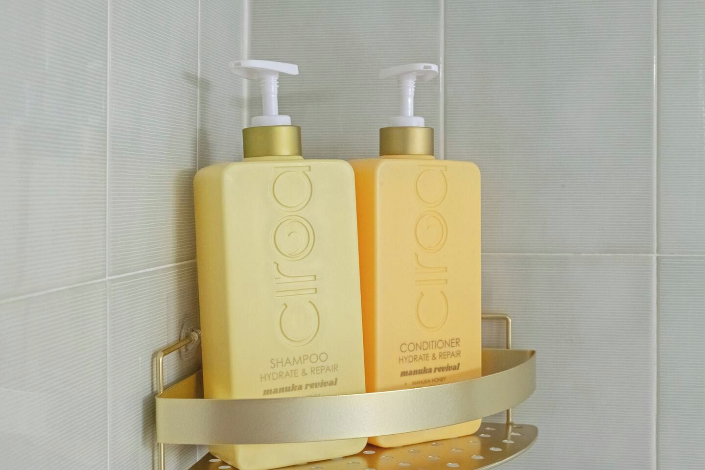 Two bottles of Ciroc shampoo and conditioner on a gold-colored shelf.