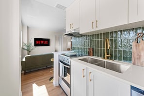 A modern kitchen with white cabinets, a stainless steel sink, and a built-in oven. - The Golden Jewel • 1BR • Parking • AC • Mins to DT (Edmonton)