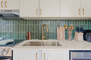 A kitchen with a stainless steel sink, a wooden cutting board, and a knife block. - The Golden Jewel • 1BR • Parking • AC • Mins to DT (Edmonton)