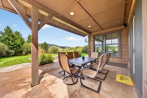 Eine Außenpatio mit Tisch und Stühlen, einem überdachten Bereich und Blick auf die umliegende Landschaft.
