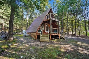 A cabin with a wooden exterior, a metal roof, and a wooden deck.