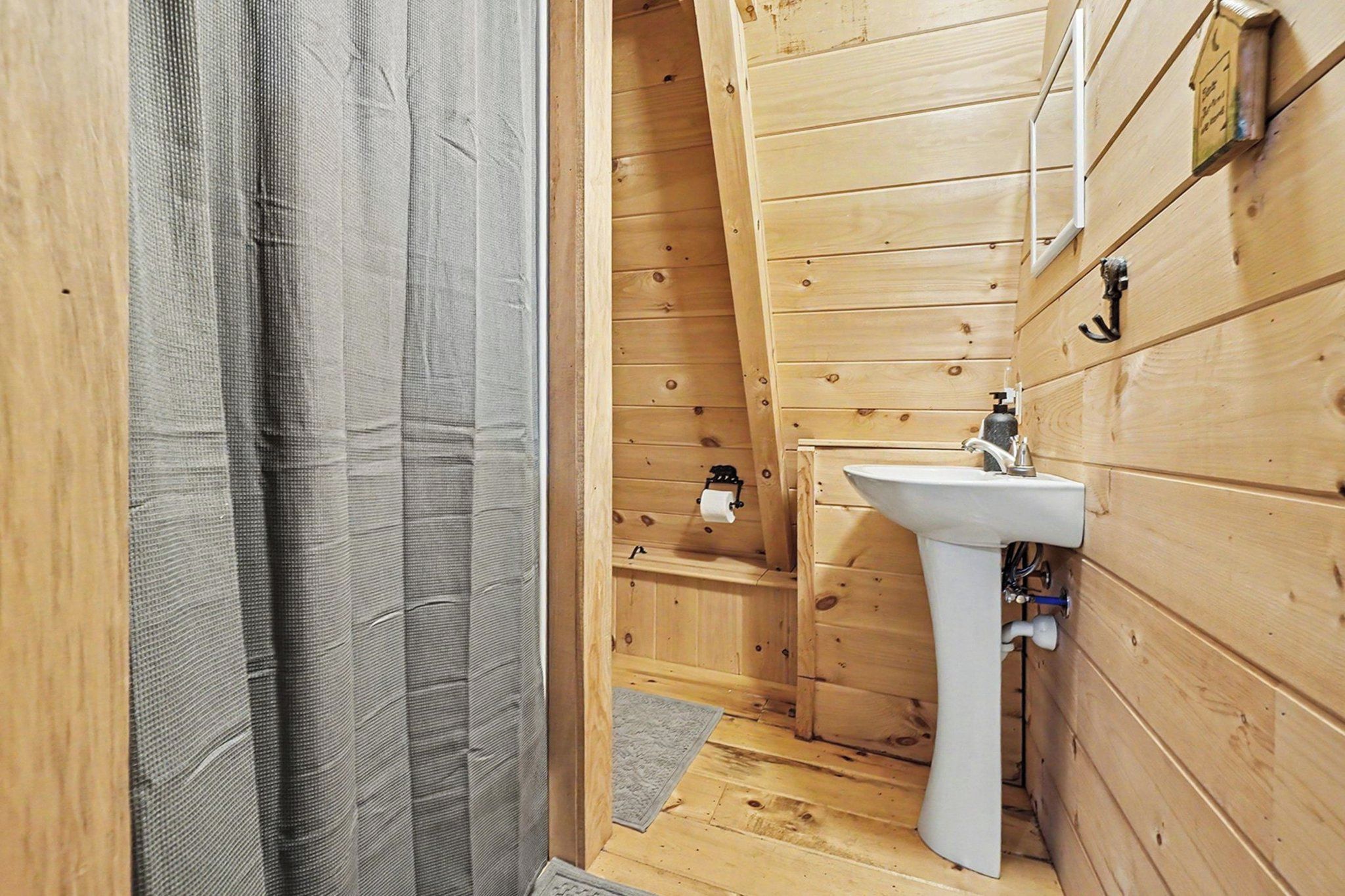 Un intérieur en bois avec un évier blanc et un espace douche.