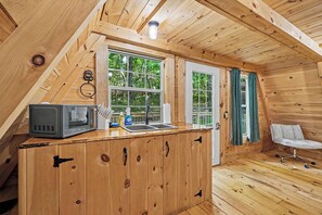 Une cuisine de taille réduite, équipée d’un four à micro-ondes, d’un évier et de meubles de rangement en bois.