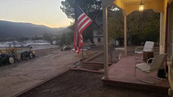 A covered outdoor area with a flag, chairs, and a tractor.