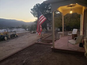 A covered outdoor area with a flag, chairs, and a tractor. - Restored 1930s Dehesa Valley Farmhouse, close to Sycuan Casino and more! (El Cajon)