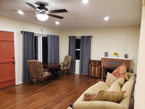 A living room with a sofa, two armchairs, a dining table, and a fireplace. - Restored 1930s Dehesa Valley Farmhouse, close to Sycuan Casino and more! (El Cajon)