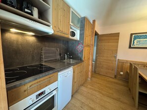 A compact kitchen with a stove, microwave, and dishwasher. - Appartement T3 pour 7 personnes avec grand balcon - Résidence Antarès (Risoul)