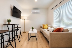 Uma sala de estar moderna com um sofá, uma mesa de centro e uma TV fixada na parede.