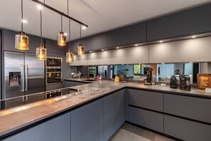 Eine moderne Küche mit Edelstahlgeräten, einer Holzarbeitsplatte und Pendelleuchten.