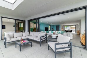 Ein modernes Wohnzimmer mit einem Ecksofa, einem Couchtisch und einer Glastür, die auf einen Balkon führt.