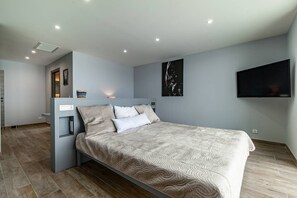 Ein modernes Schlafzimmer mit einem Bett, einem Flachbildfernseher und einem an der Wand befestigten Kunstwerk.
