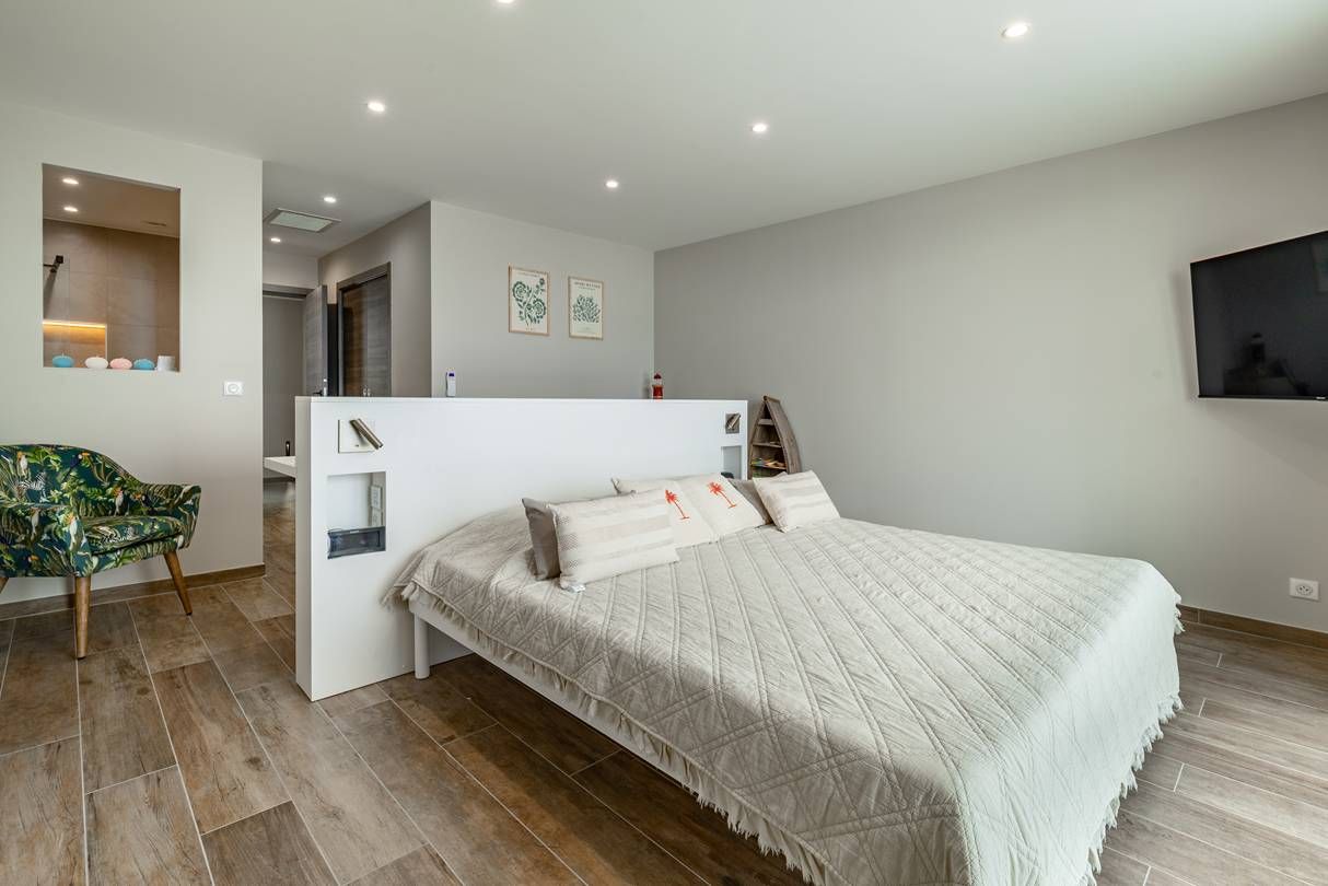 Quarto com cama, uma cadeira e um pequeno espaço de trabalho.