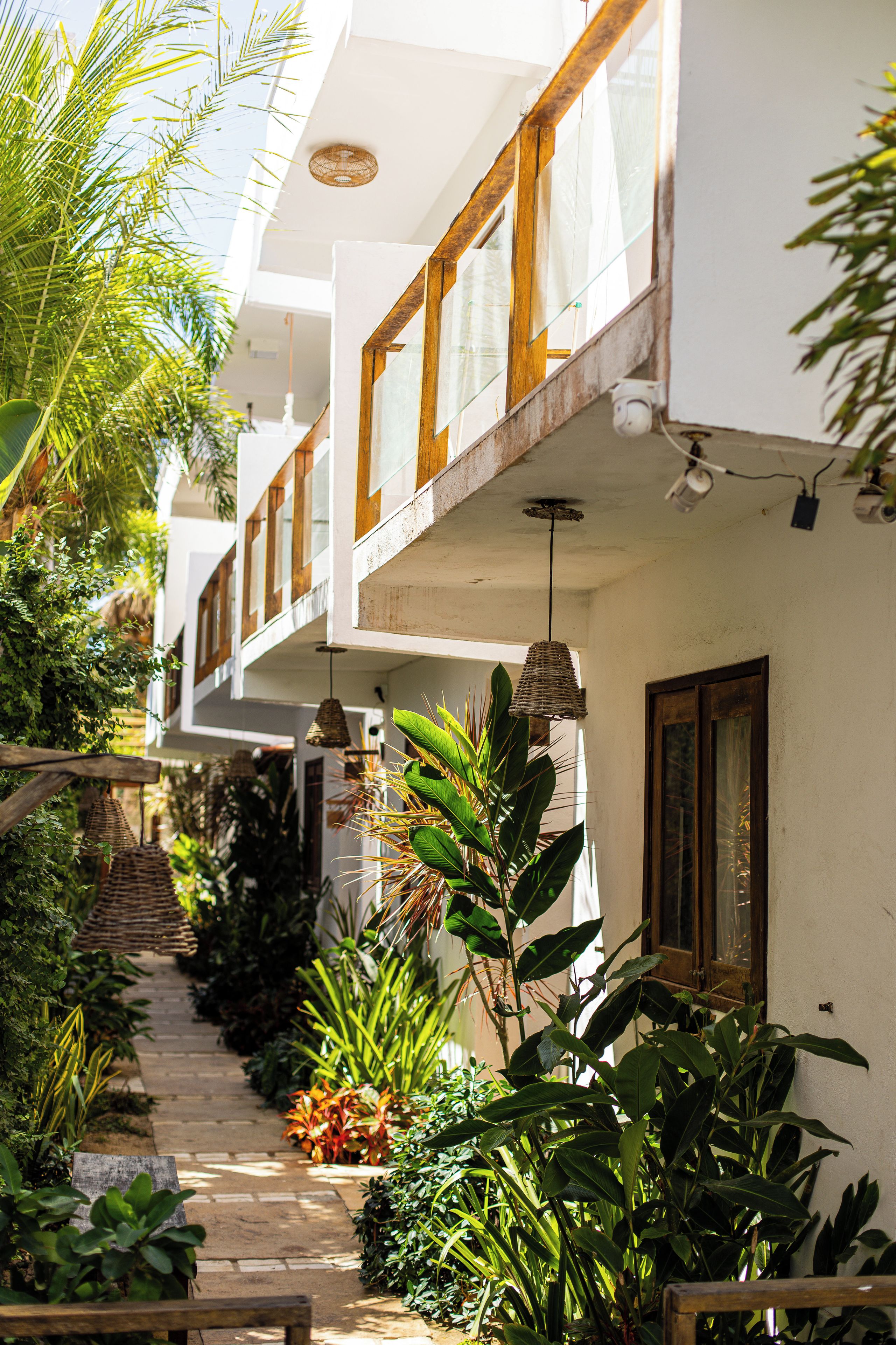 A building with multiple balconies, a covered outdoor area with plants, and a pathway leading to the entrance.