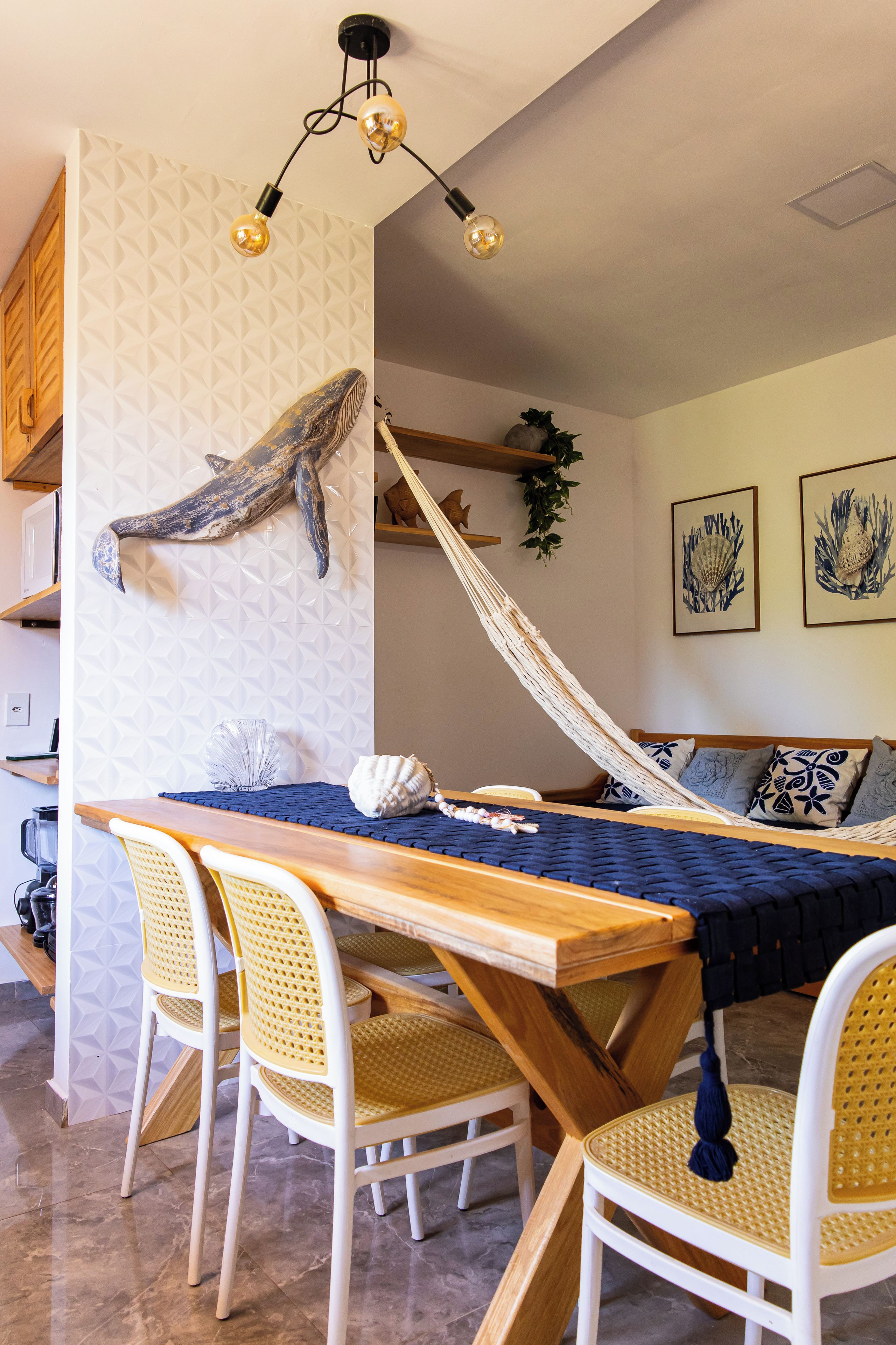 Een eetgedeelte met een houten tafel, rieten stoelen en een hangmat.