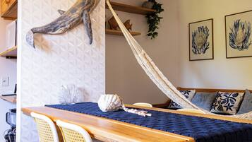Een eetgedeelte met een houten tafel, rieten stoelen en een hangmat.