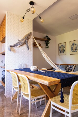 Een eetgedeelte met een houten tafel, rieten stoelen en een hangmat.