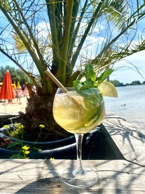 Un verre contenant une boisson, des feuilles de menthe et une tranche de citron, posé sur une surface en bois.