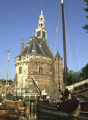A historic building with a tower and a large ship docked in front. - The Beach House - 3 Bedrooms (Schellinkhout)