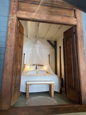 Ein Zimmer mit einem Bett unter einem Baldachin, einer Holzbank und einer Tür.