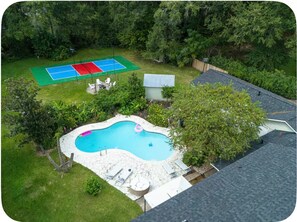 Ein Garten mit Schwimmbad, Tennisplatz und einem kleinen Schuppen.