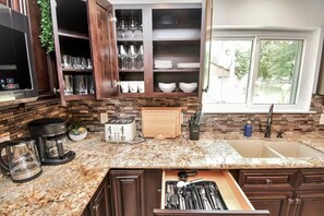 Una cocina con encimera de granito, tostadora, cafetera y pileta.