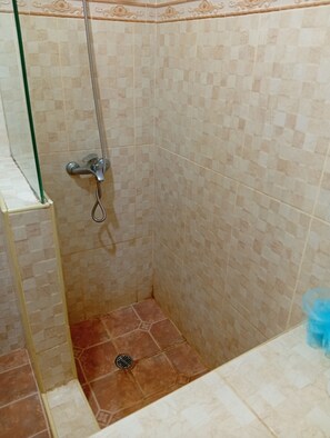 A shower area with tiled walls, a showerhead, and a drain. - APARTMENT WITH A PRIVATE TERRACE (Sosúa)