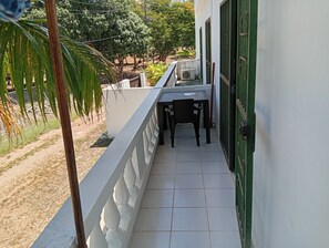 A balcony with a table and chairs, a green door, and a white wall. - APARTMENT WITH A PRIVATE TERRACE (Sosúa)