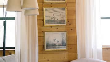L’intérieur d’une cabane avec des murs en bois, un canapé, un fauteuil et trois tableaux encadrés accrochés au mur.