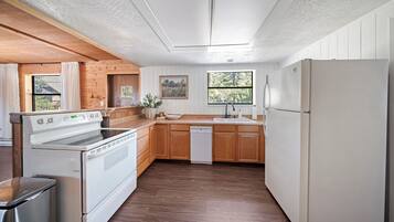 A kitchen with wooden cabinets, a white refrigerator, and a dishwasher.