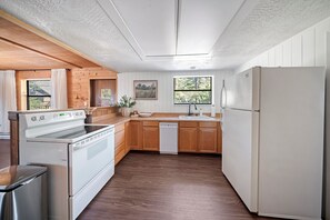 A kitchen with wooden cabinets, a white refrigerator, and a dishwasher.